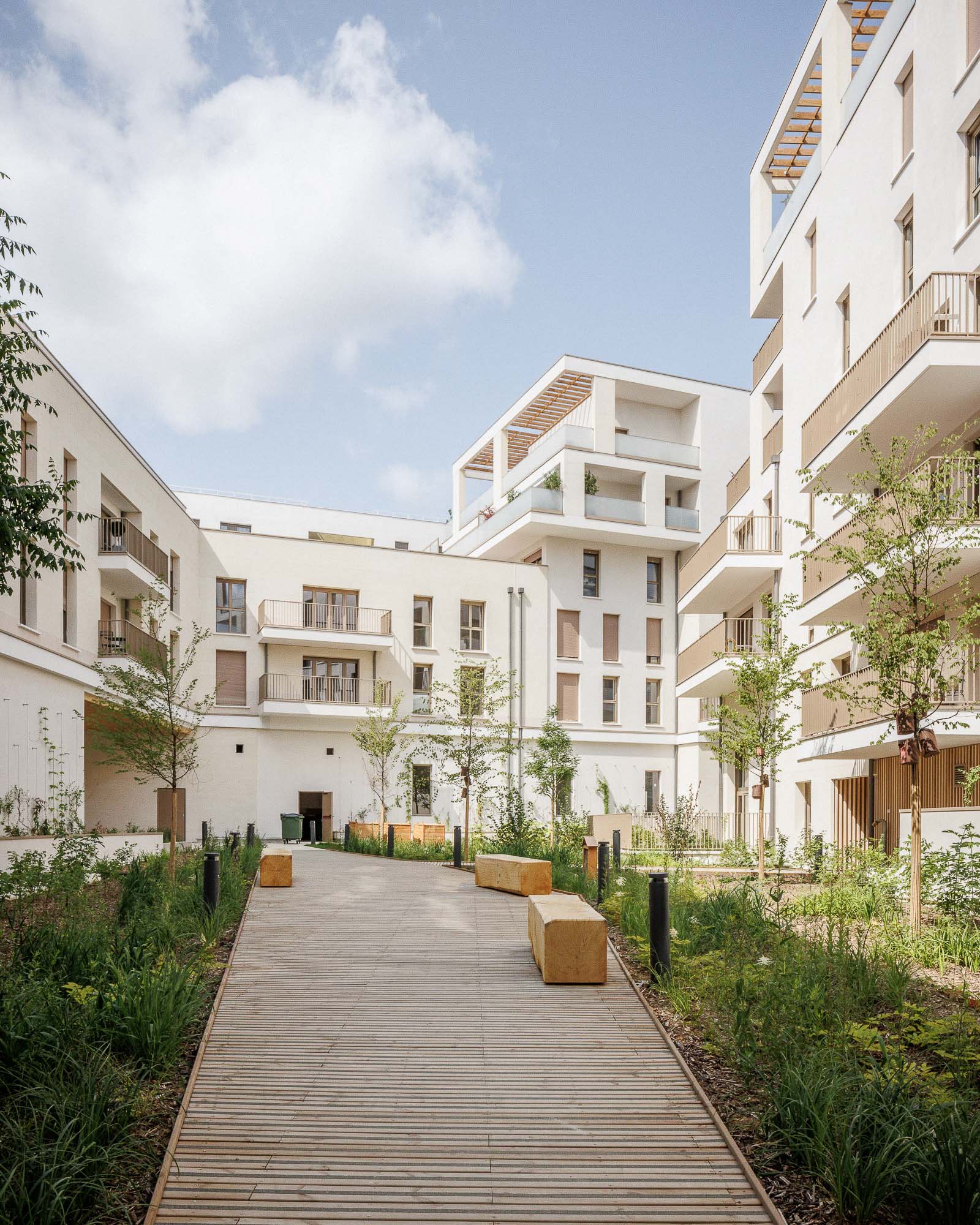 Cheminement en bois et végétation en cœur d'îlot d'un immeuble de logements contemporain de différentes échelles ZAC Jean Zay à Antony par Cussac Architectes et Associés (ca+a)